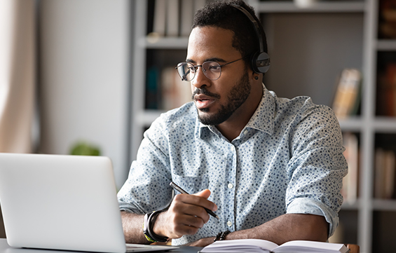 male teacher on laptop looking at exam management services
