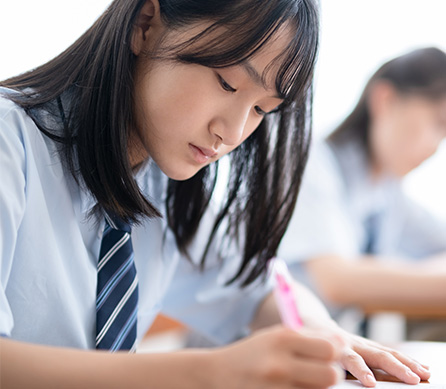 female asian student completing her scholarship exams